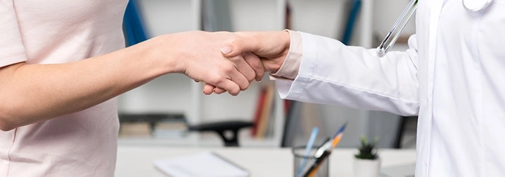 Close-up of a healthcare professional in a white coat shaking hands